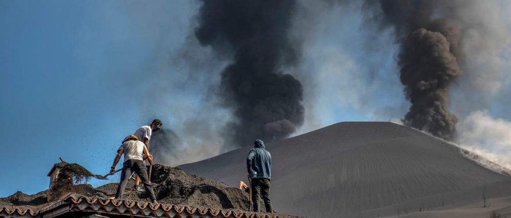 Menschen säubern ein Haus von der Asche des Vulkans in Las Manchas auf der Kanareninsel La Palma. 