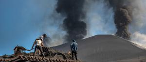 Menschen säubern ein Haus von der Asche des Vulkans in Las Manchas auf der Kanareninsel La Palma. 