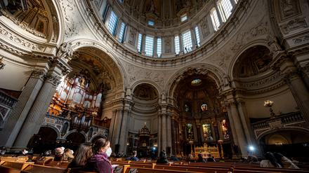 Besucher sitzen mit Maske im Berliner Dom