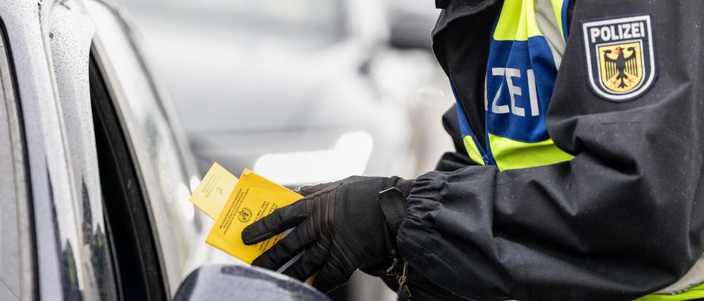 Ein Bundespolizist kontrolliert einen Impfpass.