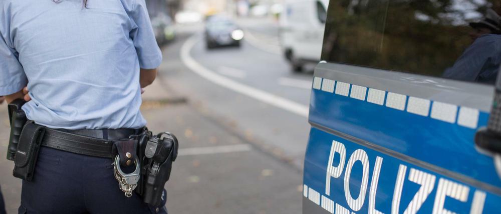 Eine Polizistin steht neben einem Streifenwagen mit dem Schriftzug Polizei. (Symbolbild)