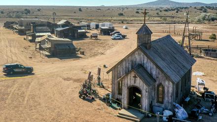 Ein Polizeifahrzeug fährt auf der Bonanza Creek Ranch an einem Gebäude vorbei, das von einem gelben Polizeiabsperrungsband umgeben ist.