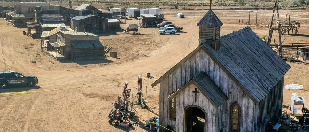 Ein Polizeifahrzeug fährt auf der Bonanza Creek Ranch an einem Gebäude vorbei, das von einem gelben Polizeiabsperrungsband umgeben ist.