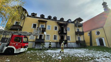 Feuerwehrleute stehen vor dem Mehrfamilienhaus in Reisbach im niederbayerischen Landkreis Dingolfing-Landau.