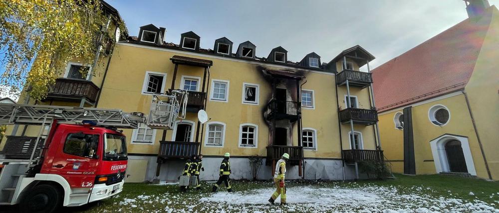 Feuerwehrleute stehen vor dem Mehrfamilienhaus in Reisbach im niederbayerischen Landkreis Dingolfing-Landau.