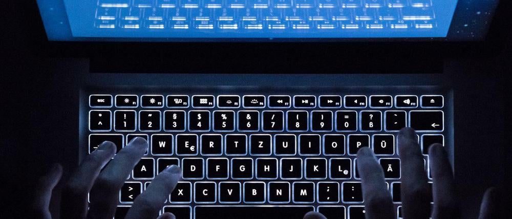 Ein Mann benutzt die beleuchtete Tastatur eines Notebooks (Szene gestellt, Symbolbild).