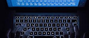 Ein Mann benutzt die beleuchtete Tastatur eines Notebooks (Szene gestellt, Symbolbild).