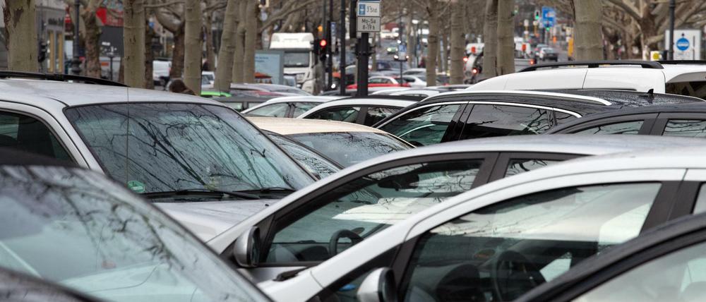 Eng aneinander geparkte Autos unter winterlichen Bäumen in Berlrin.