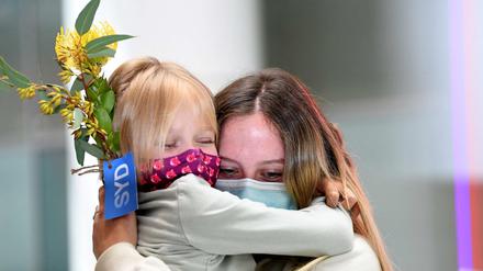 Menschen liegen sich am Flughafen in den Armen.