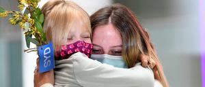 Menschen liegen sich am Flughafen in den Armen.