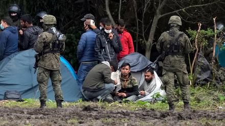 Polnische Sicherheitskräfte umringen Migranten, die an der Grenze zu Weißrussland festsitzen.