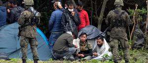 Polnische Sicherheitskräfte umringen Migranten, die an der Grenze zu Weißrussland festsitzen.