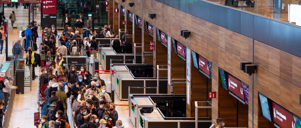 Zahlreiche Fluggäste warten im Terminal 1 des Flughafens BER in einer Schlange auf die Sicherheitskontrolle. 