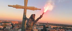 Hilferuf. Die Fackel wird mit Licht erhellt, und künstlicher Rauch kommt heraus. Fassadenkletterer brachten alles oben auf der Kreuzberger Kirche an..