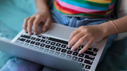 Zu sehen ist ein Laptop, auf dem ein:e Jugendliche tippt.