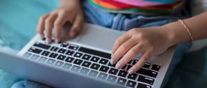 Zu sehen ist ein Laptop, auf dem ein:e Jugendliche tippt.