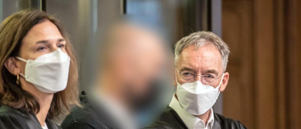 Der Angeklagte steht im Gerichtssaal zwischen seinen Anwälten. 