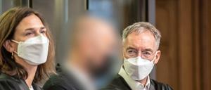 Der Angeklagte steht im Gerichtssaal zwischen seinen Anwälten. 
