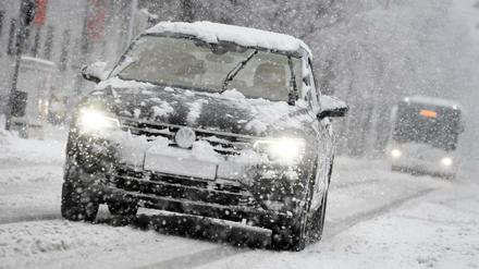 Bußgelder für Autofahrer im Winter: Ein Auto fährt bei Schneefall auf einer schneebedeckten Straße. (Archivbild)