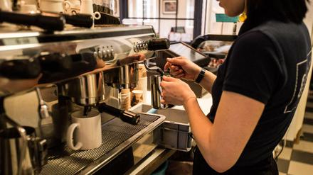 Eine Studentin jobbt im Café, hier schäumt sie Milch auf.