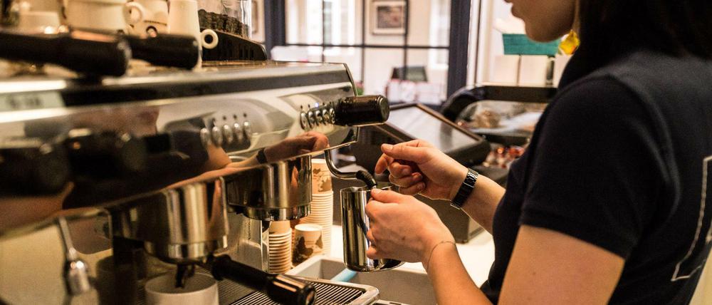 Eine Studentin jobbt im Café, hier schäumt sie Milch auf.