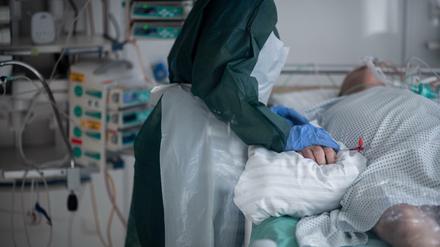 Eine Mitarbeiterin der Pflege in Schutzausrüstung betreut einen Covid-Patienten
