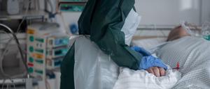 Eine Mitarbeiterin der Pflege in Schutzausrüstung betreut einen Covid-Patienten 