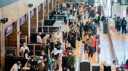Passagiere stehen am BER vor der Sicherheitskontrolle Schlange.