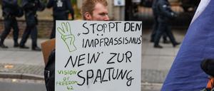 Ein Demonstrant hält ein Schild mit der Aufschrift Stoppt den Impfrassismus hoch.