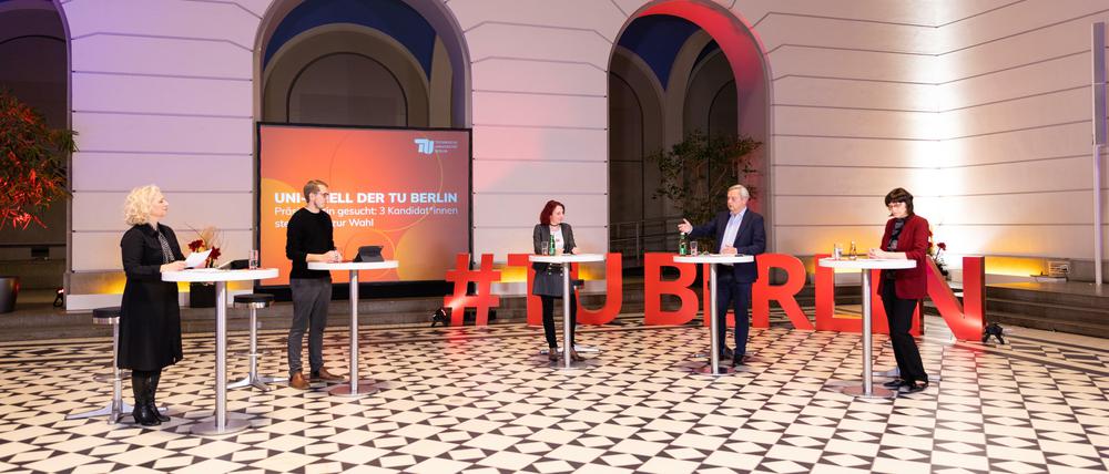Fünf Personen an Stehtischen in einem überdachten Atrium eines historischen Gebäudes.