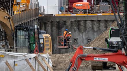 Bauarbeiter betrachten einen Tag nach der Explosion einer Fliegerbombe den Krater auf der Baustelle.