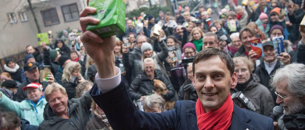 Martin Hikel (SPD, M), Bezirksbürgermeister von Berlin-Neukölln, hält beim ersten Hilfe-Flashmob «Kaffee gegen Kälte» zusammen mit zahlreichen anderen Spendern ein Paket Kaffee in die Höhe.