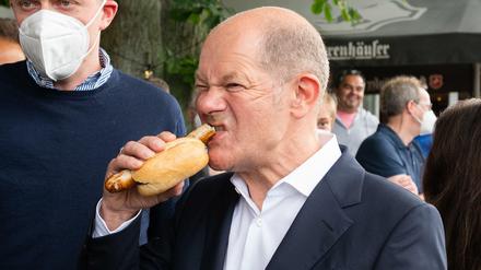 Olaf Scholz beißt in eine Bratwurst.