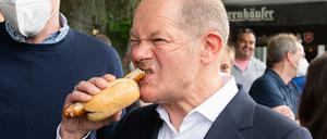 Olaf Scholz beißt in eine Bratwurst.