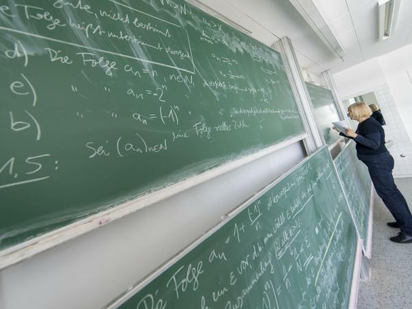 Eine Dozentin schreibt mathematische Formeln an die Tafel.