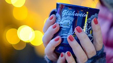 Hände umfassen eine Tasse Glühwein.