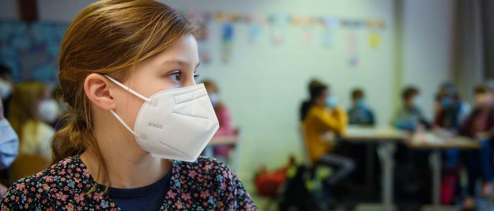 Eine Schülerin einer 4. Klasse sitzt im Unterricht an der Grundschule Russee in Kiel mit einer FFP-2-Maske an ihrem Platz.