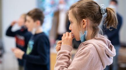 Schülerin einer vierten Klasse einer Grundschule, gibt während eines selbst durchgeführten Coronatests ihre Speichelprobe in ein Teströhrchen.