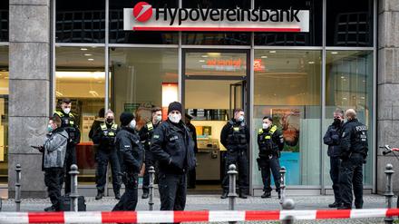 Polizisten stehen vor der Hypovereinsbank in der Friedrichstraße. Bankräuber haben die Bank überfallen und mehrere Menschen mit Reizgas verletzt.