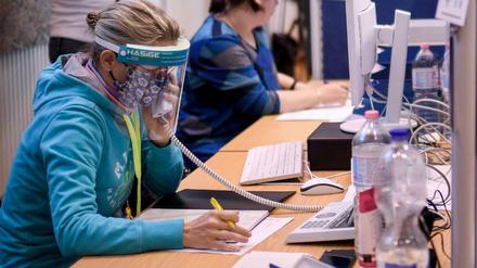 Mitarbeiter des Gesundheitsamtes Mitte mit Gesichtsschutzschirm telefonieren in einem Berliner Lagezentrum
