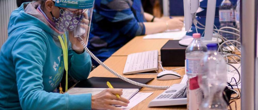 Mitarbeiter des Gesundheitsamtes Mitte mit Gesichtsschutzschirm telefonieren in einem Berliner Lagezentrum