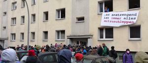 Unterstützter sammeln sich vor dem Haus in Mitte. Aus den Fenstern hängen Transparente. 