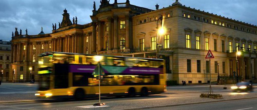 Ein Bus fährt vorbei an der Alten Bibliothek (Kommode) am Bebelplatz in der Straße Unter den Linden im Berliner Bezirk Mitte.