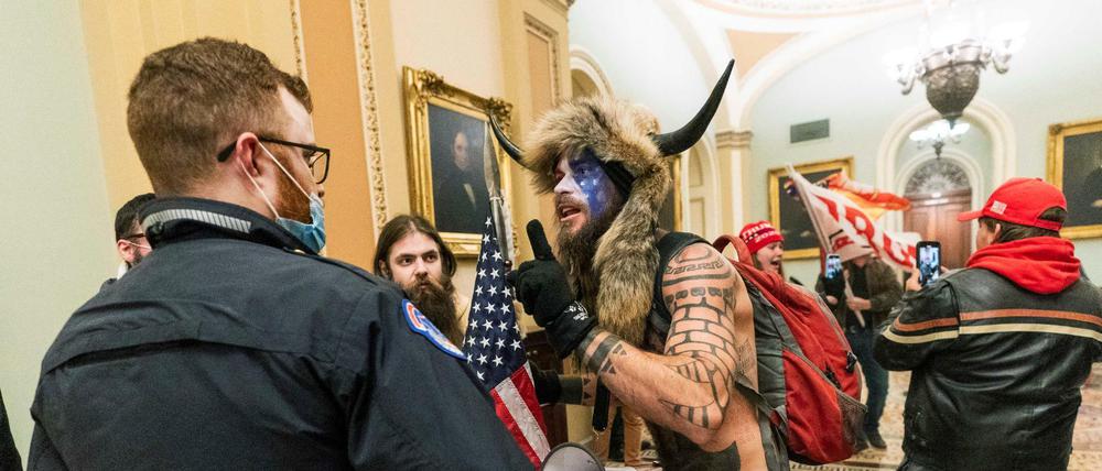 Ein Unterstützer von US-Präsident Trump steht auf dem Gang vor der Senatskammer im US-Kapitol und diskutiert mit einem Polizisten des Kapitols.