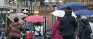 Passanten in Hamburg schützen sich auf dem Rathausmarkt mit Regenschirmen vor dem Dauerregen.