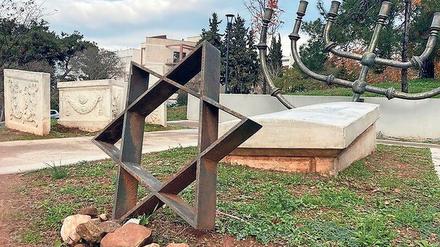 Mahnmal an den jüdischen Friedhof mit einigen Grabsteinen, einem Davidstern und einer Menora als Symbole.