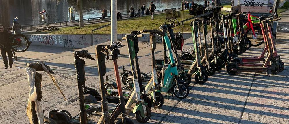 E-Roller, die von der Organisation Spree:publik aus der Spree gefischt wurden, stehen in einer Reihe am Ufer.