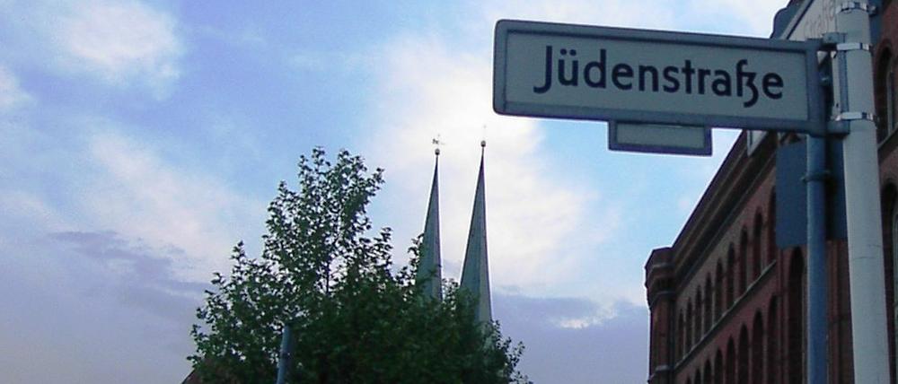 Straßenschild der Jüdenstraße am Roten Rathaus in Berlin-Mitte vor leicht bewölktem Himmel.