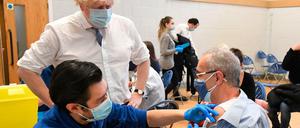 Boris Johnson (2.v.l), Premierminister von Großbritannien, beobachtet eine Booster-Impfung