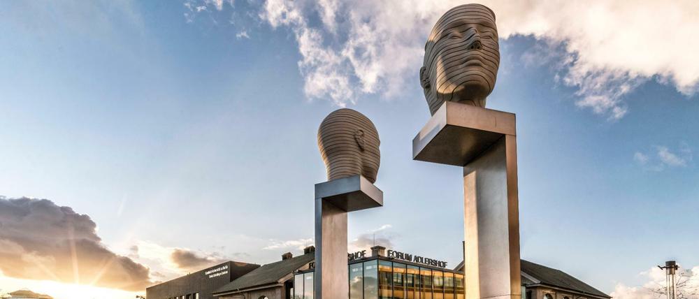 Skulptur mit zwei drehenden Köpfenn auf Säulen auf einem Uni-Campus.